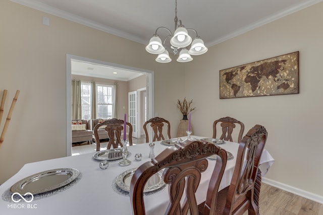 dining space with an inviting chandelier, ornamental molding, and light hardwood / wood-style flooring