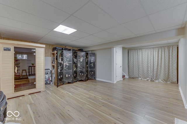 basement featuring a paneled ceiling and light wood-type flooring