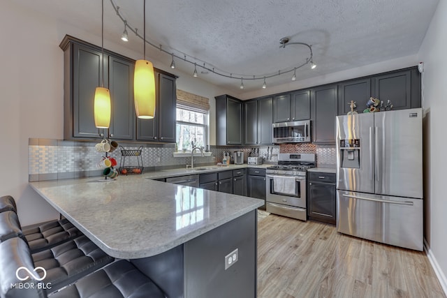 kitchen featuring appliances with stainless steel finishes, sink, pendant lighting, and kitchen peninsula