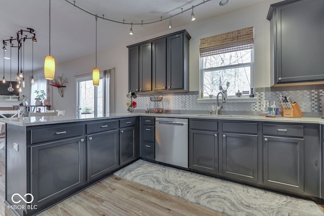 kitchen with decorative light fixtures, tasteful backsplash, dishwasher, sink, and kitchen peninsula