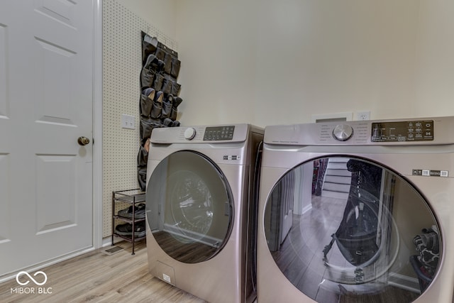 clothes washing area with light wood-type flooring and independent washer and dryer