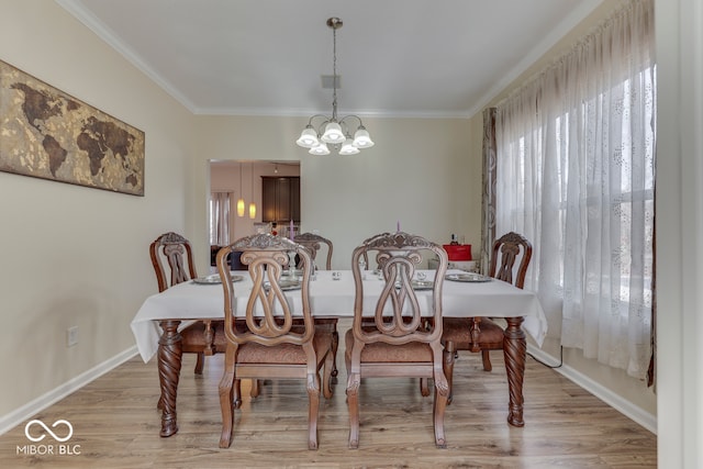 dining area with crown molding, a chandelier, and light wood-type flooring