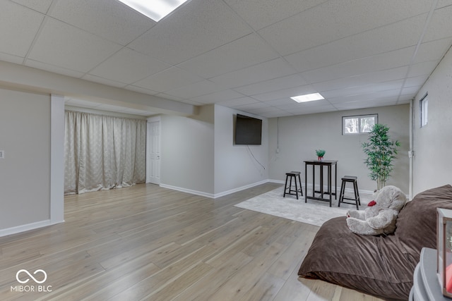 living room featuring a paneled ceiling and light hardwood / wood-style flooring