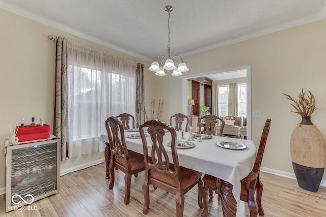 dining space with crown molding, a notable chandelier, and light wood-type flooring