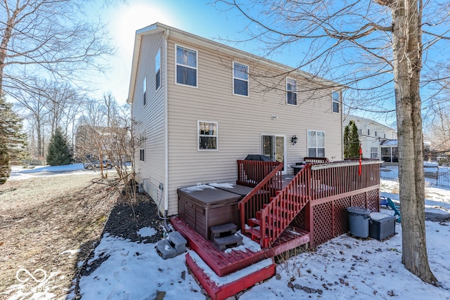 snow covered rear of property featuring a wooden deck and a hot tub