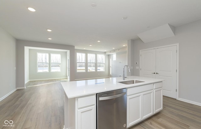 kitchen with sink, light hardwood / wood-style flooring, stainless steel dishwasher, a kitchen island with sink, and white cabinets