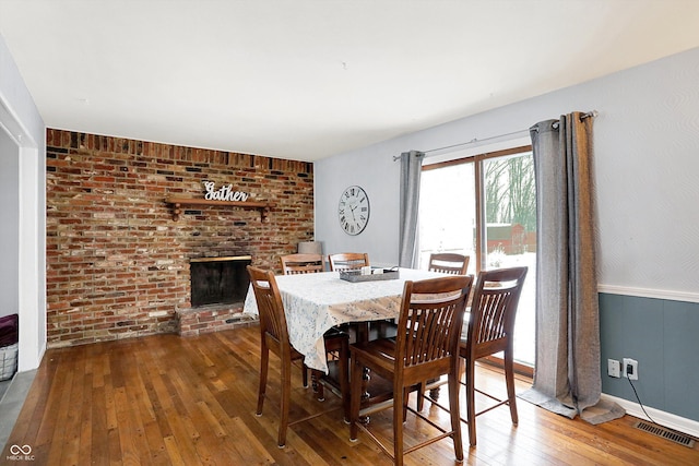 dining space with a brick fireplace and wood-type flooring