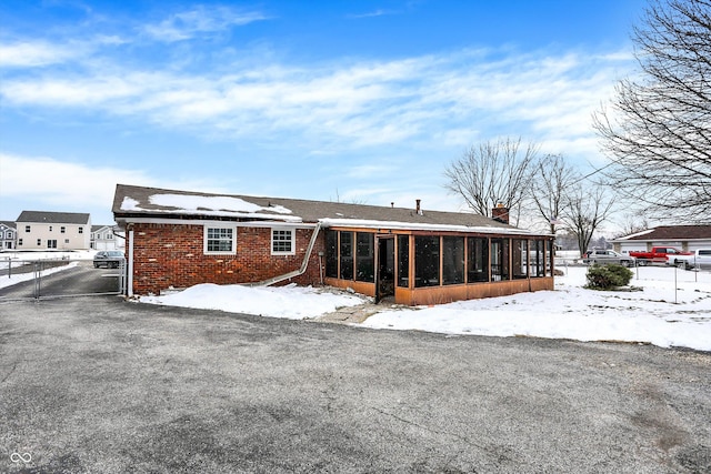 snow covered property featuring a sunroom