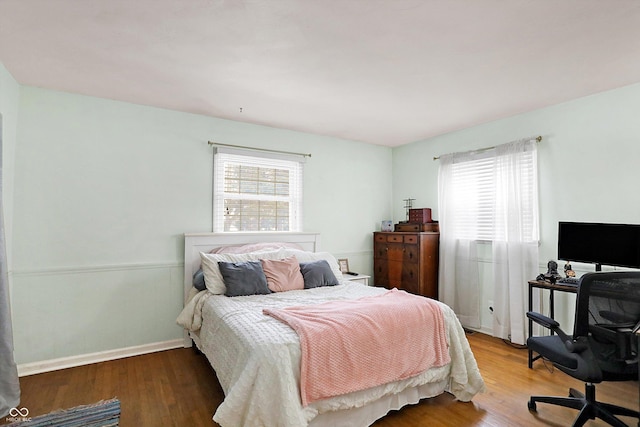 bedroom with hardwood / wood-style flooring and multiple windows