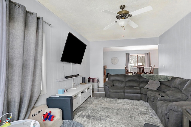 living room featuring ceiling fan and a textured ceiling