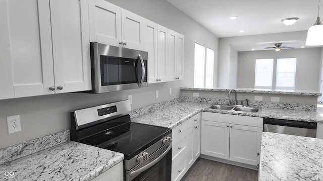 kitchen featuring sink, pendant lighting, stainless steel appliances, light stone countertops, and white cabinets