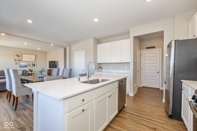 kitchen with sink, white cabinets, stainless steel appliances, a center island with sink, and light hardwood / wood-style flooring