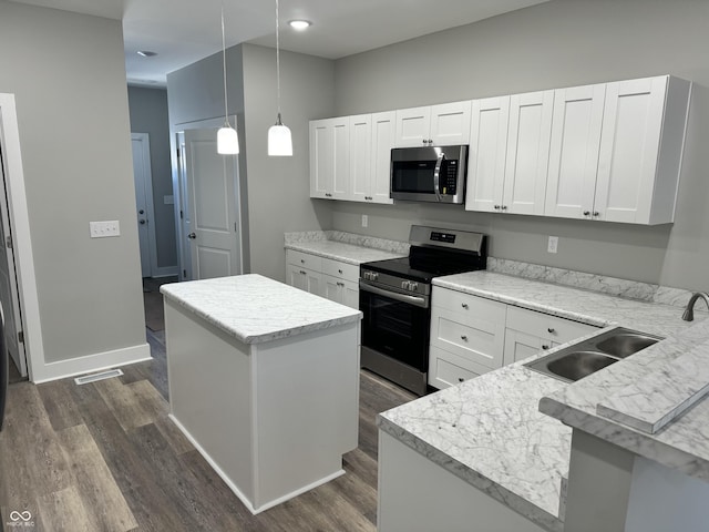 kitchen featuring appliances with stainless steel finishes, hanging light fixtures, a kitchen island, and white cabinets