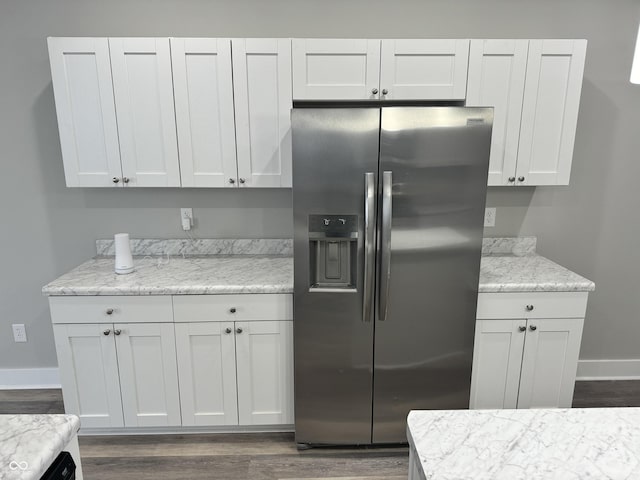 kitchen with stainless steel refrigerator with ice dispenser, light stone counters, and white cabinets