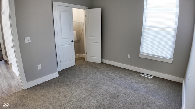 unfurnished bedroom featuring a closet, a spacious closet, and light carpet