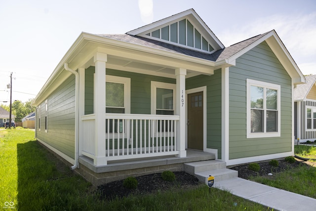 1407 N Pershing Ave, Indianapolis, IN 46222 - view of front of home with covered porch, a shingled roof, a front lawn, and board and batten siding