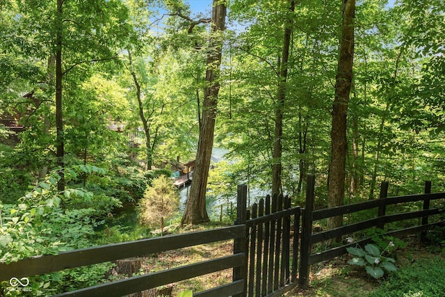 view of gate featuring fence and a view of trees