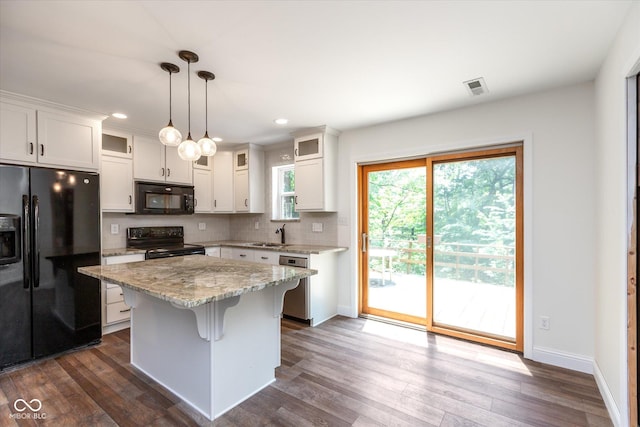 kitchen with hanging light fixtures, black appliances, a center island, and white cabinetry