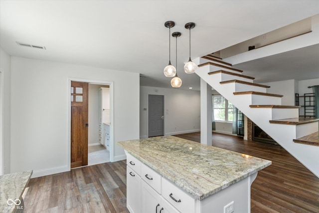 kitchen with dark wood-style floors, pendant lighting, visible vents, white cabinets, and light stone countertops