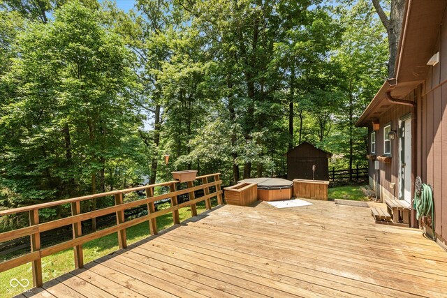 wooden terrace featuring an outbuilding, a shed, and a jacuzzi