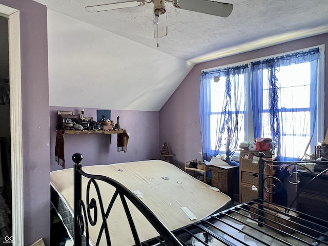 bedroom with ceiling fan, lofted ceiling, and a textured ceiling