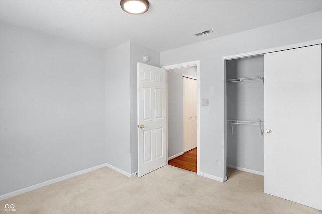 unfurnished bedroom with light carpet and a closet