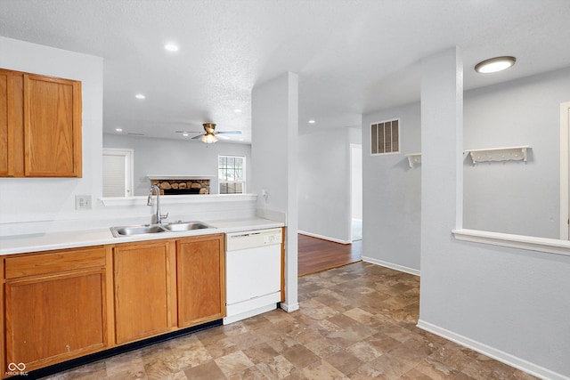 kitchen with ceiling fan, white dishwasher, sink, a fireplace, and a textured ceiling