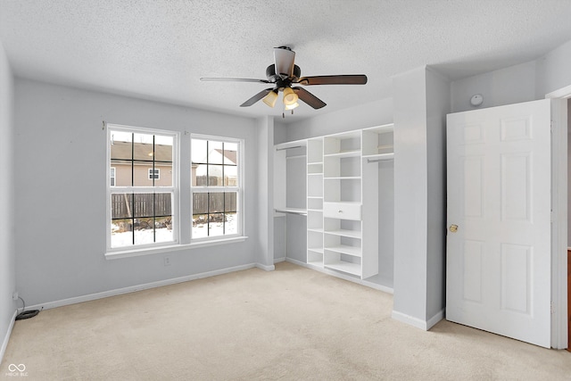 unfurnished room with ceiling fan, light colored carpet, and a textured ceiling