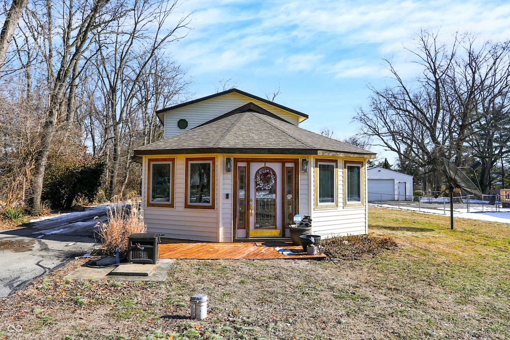 bungalow with a garage, an outdoor structure, and a front yard