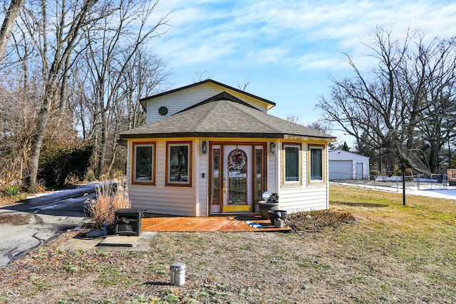 bungalow with a garage, an outdoor structure, and a front yard