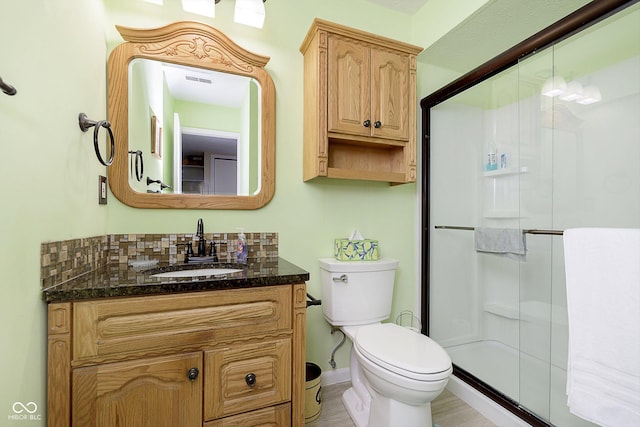 bathroom with walk in shower, vanity, toilet, and backsplash