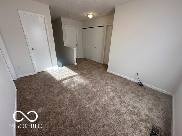 unfurnished bedroom with a textured ceiling, carpet flooring, and a closet