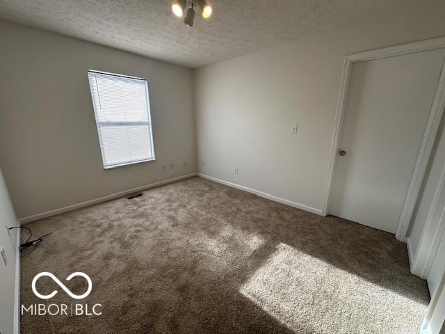 carpeted empty room with a textured ceiling