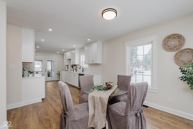 dining space featuring sink, light wood-type flooring, and french doors