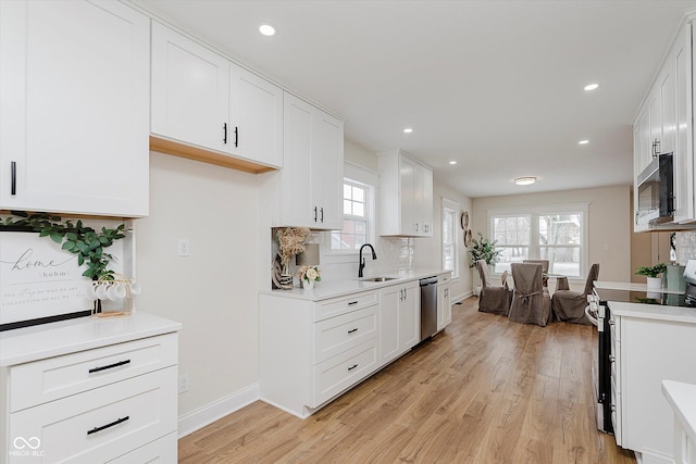 kitchen featuring stainless steel appliances, sink, white cabinets, and light wood-type flooring