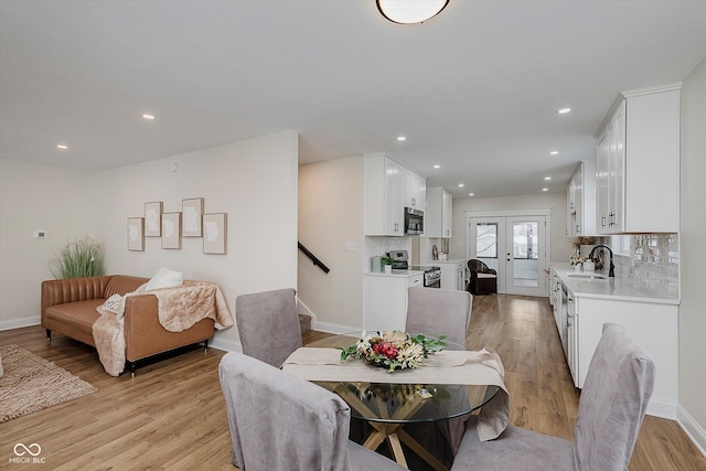 dining space with sink, french doors, and light wood-type flooring