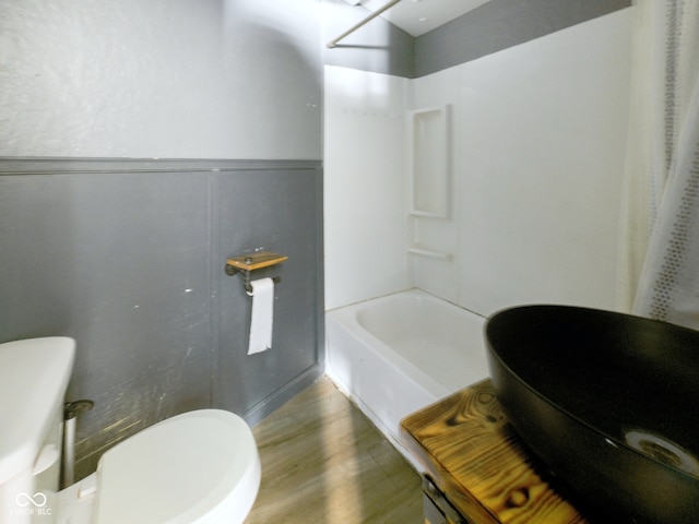 bathroom featuring hardwood / wood-style flooring, shower / tub combo with curtain, and toilet