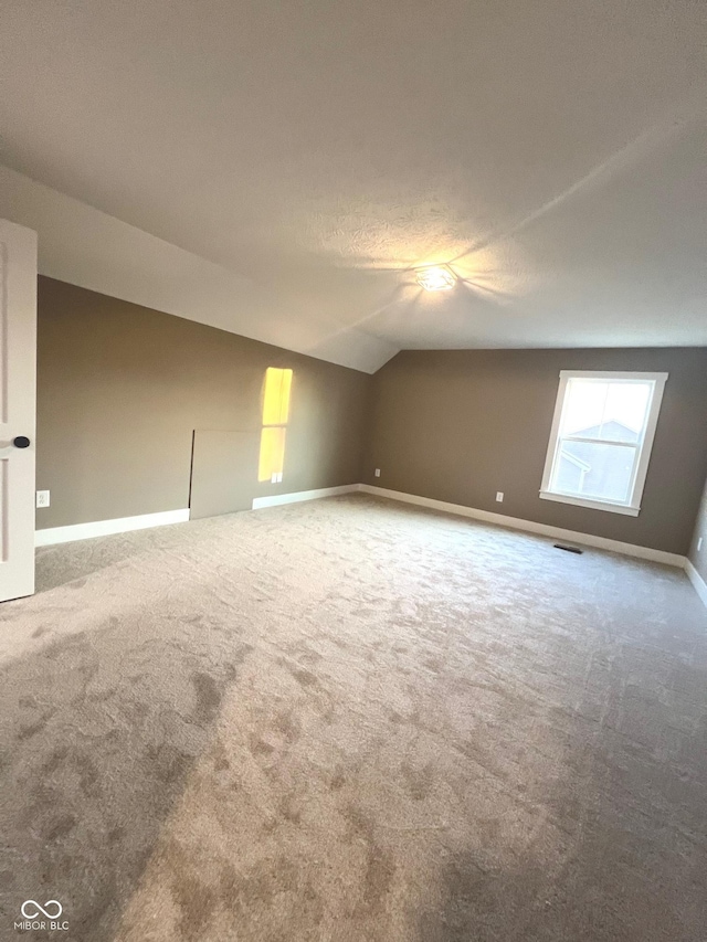 additional living space featuring lofted ceiling and carpet