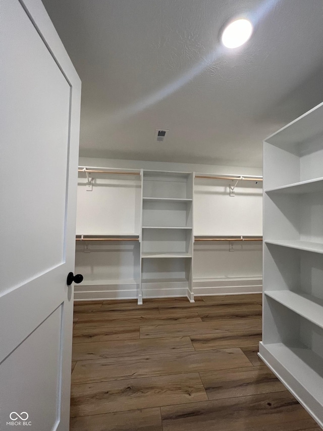 spacious closet with dark hardwood / wood-style flooring