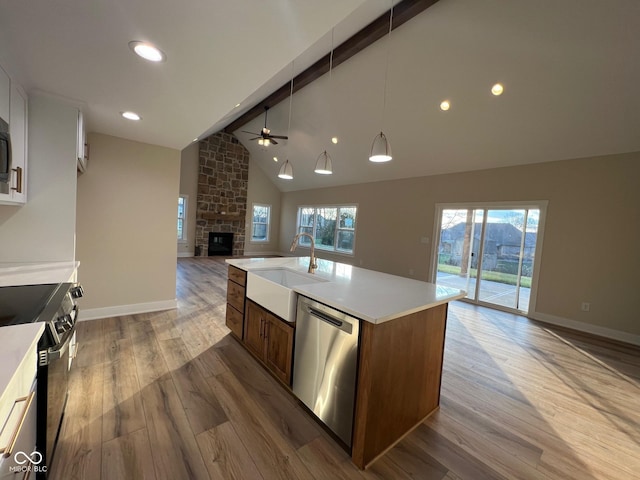 kitchen featuring range with electric stovetop, sink, stainless steel dishwasher, a center island with sink, and beam ceiling