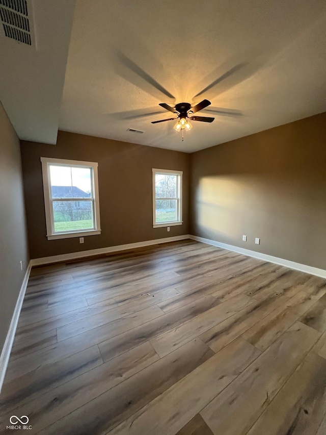 empty room with ceiling fan, light hardwood / wood-style flooring, and a healthy amount of sunlight