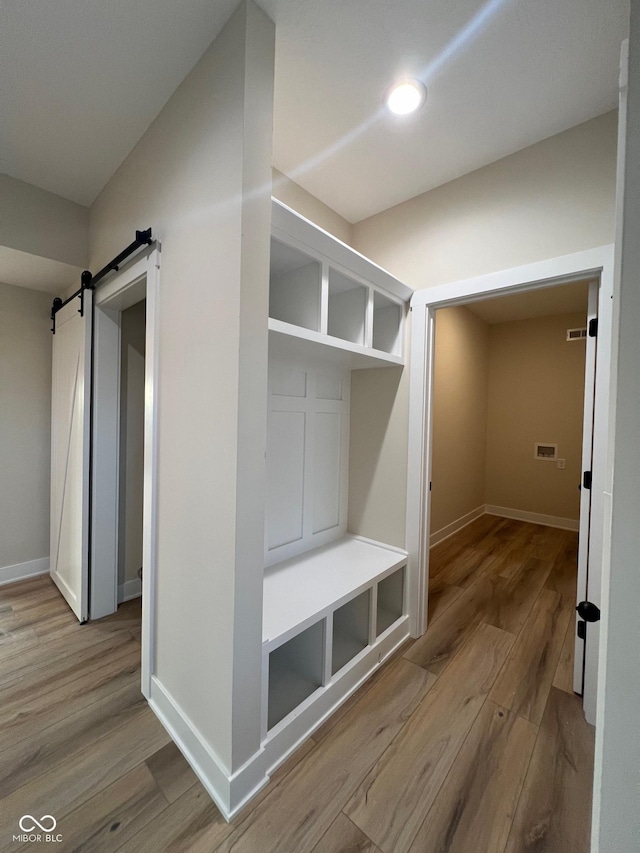 mudroom featuring a barn door and light hardwood / wood-style floors