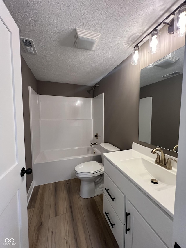 full bathroom featuring vanity, tub / shower combination, hardwood / wood-style floors, and a textured ceiling