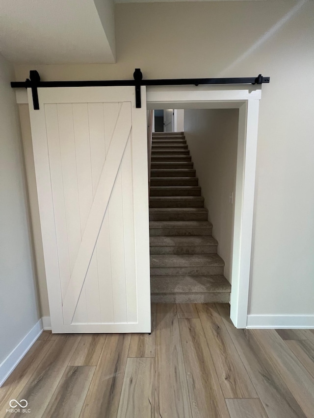 stairway with a barn door and hardwood / wood-style floors