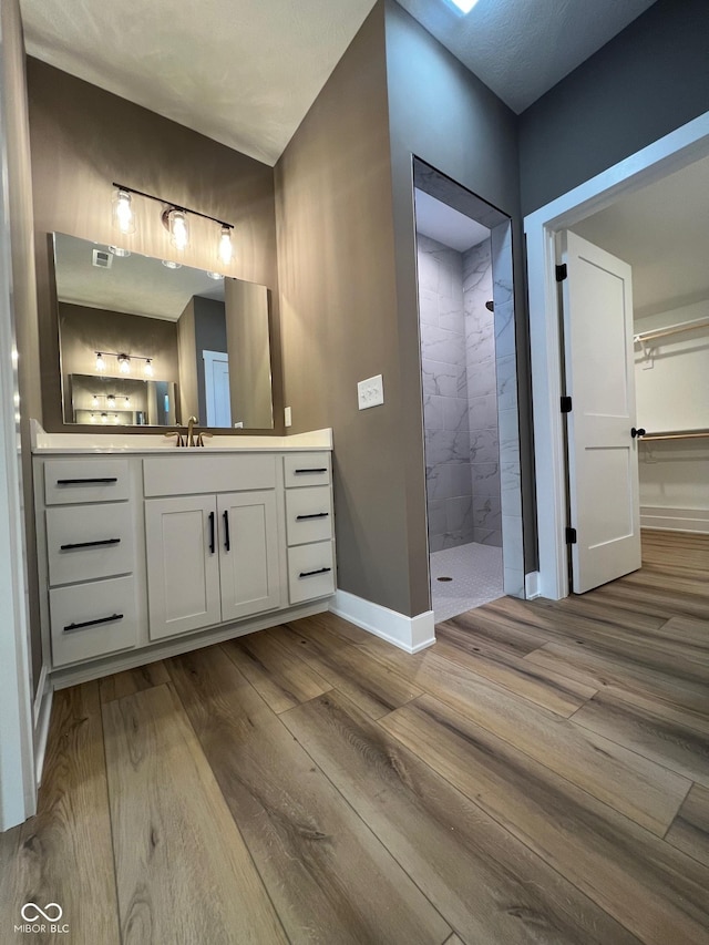 bathroom with vanity, hardwood / wood-style floors, and tiled shower