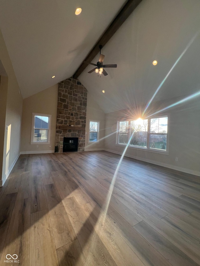 unfurnished living room featuring vaulted ceiling with beams, wood-type flooring, a fireplace, and a healthy amount of sunlight