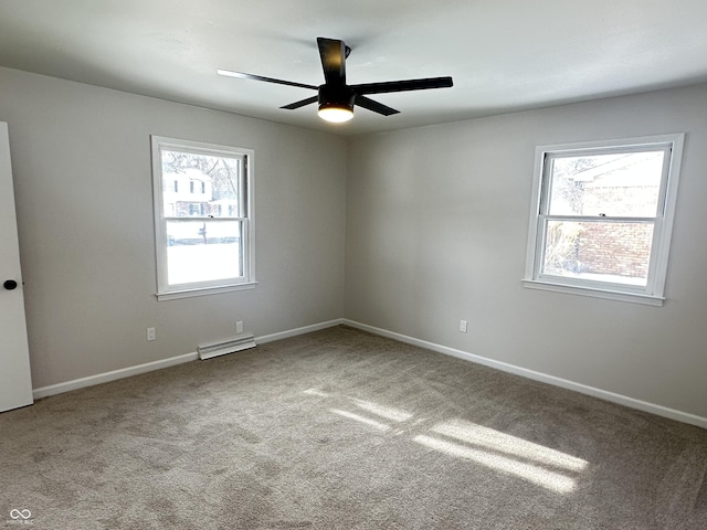 empty room featuring light carpet, ceiling fan, a wealth of natural light, and a baseboard radiator