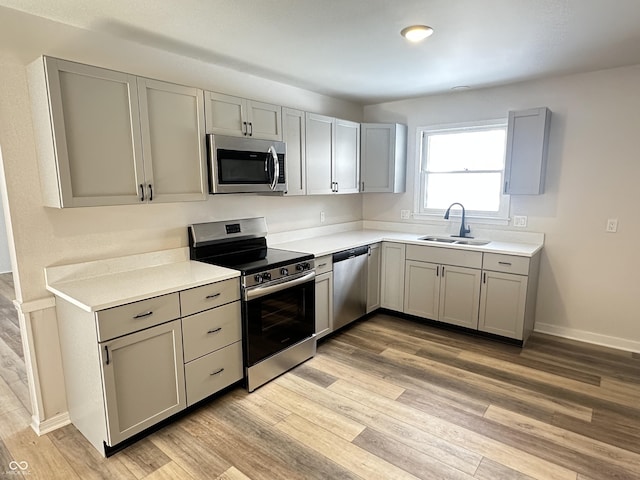 kitchen with sink, gray cabinets, stainless steel appliances, and light hardwood / wood-style floors