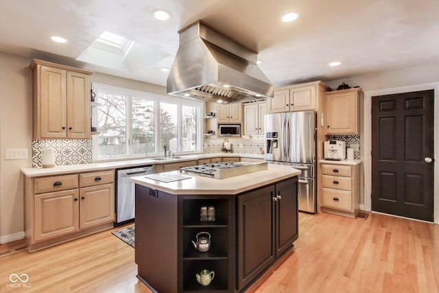 kitchen with appliances with stainless steel finishes, a skylight, island exhaust hood, a center island, and light hardwood / wood-style flooring