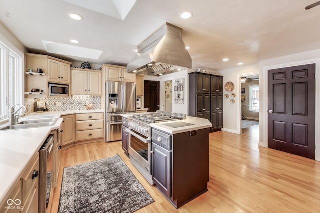 kitchen featuring sink, island range hood, a skylight, appliances with stainless steel finishes, and decorative backsplash